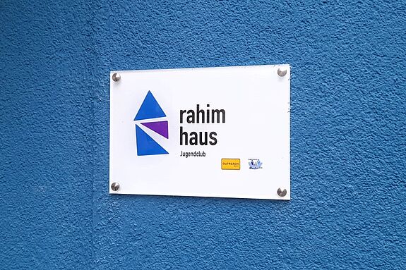 Auf der blauen Fassade ist ein Schild mit dem Namen des Jugendtreffpunkts Rahim-Yildirim-Haus angebracht. 