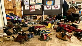 Viele verschiedene Schuhe stehen durcheinander in einem Raum. 