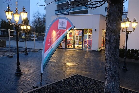 Vor dem Eingang des Quartiersbüros Hellersdorfer Promenade stehen ein Aufsteller und leuchtende Laternen.