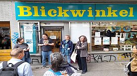 Mehrere Menschen stehen vor dem Büro des Vereins Blickwinkel e.V.[SS28.1] und unterhalten sich. 