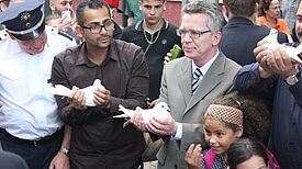 Yousef Ayoub (2.v.l.) mit Bundesinnenminister Thomas de Maizière  (2.v.r.) bei einer gemeinsamen Aktion für ein friedliches Miteinander im Soldiner Kiez. Foto: KbNA e.V.