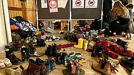 Viele verschiedene Schuhe stehen durcheinander in einem Raum. 