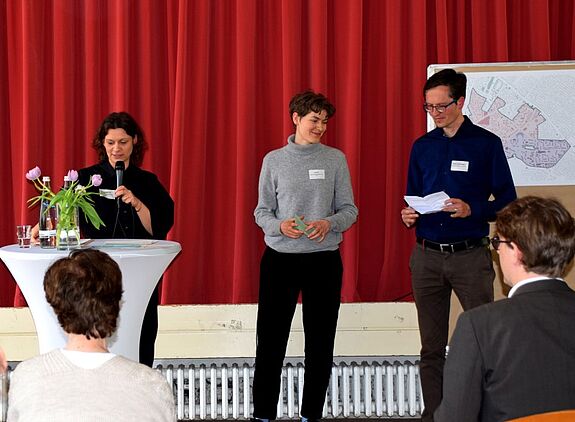 Die Moderatorin Claudia Hoffmeister interviewt Thorsten Vorberg-Begrich (QM-Team) und Jac Diallo (Team Modellvorhaben) zu ihren jeweiligen Fördergebieten. (Bild: QM Gropiusstadt Nord)