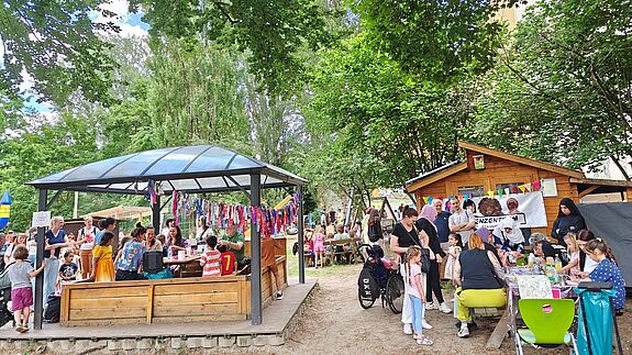 Kinder und Erwachsene feiern das Jubiläum der Wilden Rübe und der Kita in der Wildenbruchstraße im Freien.