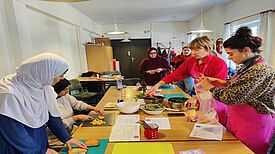 Stadtteilmütter schneiden Gemüse und bereiten Speisen in einem Workshop zur Vermeidung von Lebensmittelverschwendung vor.