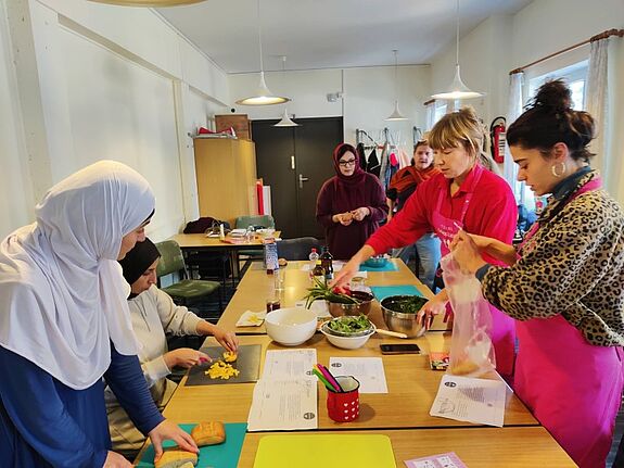 Stadtteilmütter schneiden Gemüse und bereiten Speisen in einem Workshop zur Vermeidung von Lebensmittelverschwendung vor.