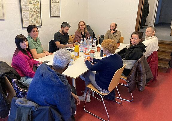 Eine Gruppe von Personen sitzt an einem Tisch mit zahlreichen Getränken.