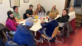 Eine Gruppe von Personen sitzt an einem Tisch mit zahlreichen Getränken.