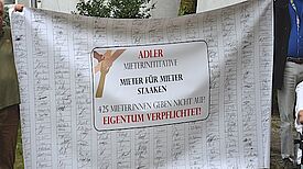 Ein Plakat zeigt viele gesammelte Unterschriften der „Adler-Mieterinitiative“. 
