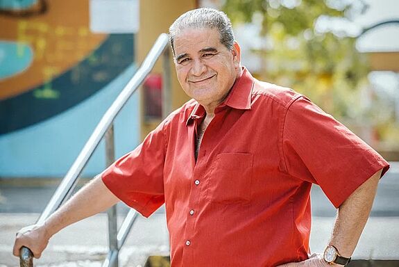 Ibrahim Kassab steht auf einer Treppe in der High-Deck-Siedlung und lächelt.