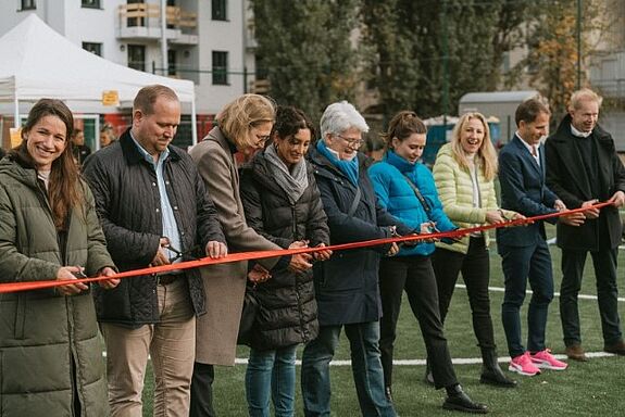 Projektbeteiligte schneiden symbolisch das Band durch, um die Eröffnung des Sportplatzes zu symbolisieren. (Bild: Amandla gGmbH)