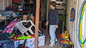 Ein Junge steht im Spielecontainer am Klara-Franke-Spielplatz, umgeben von Spielgeräten und Spielsachen.