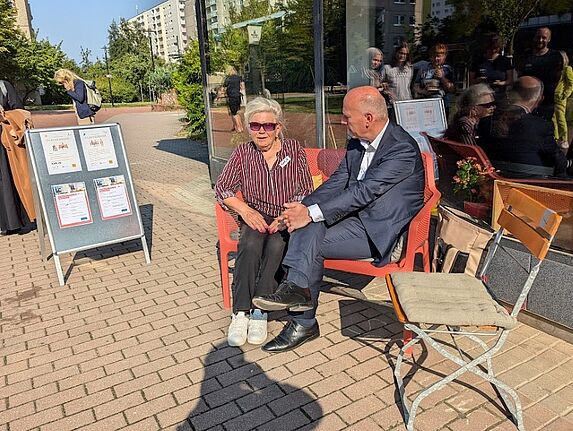 Der Regierende Bürgermeister Kai Wegner plaudert mit einer engagierten Bewohnerin auf der Plauderbank über den Kiez. (Bild: Joachim Schmidt)