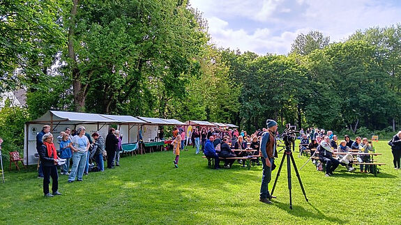 Zahlreiche Menschen besuchten das Stadtteilfest im Volkspark Lichtenrade, mit Ständen, Sitzbänken und viel Grün im Hintergrund.