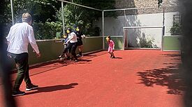 Kinder und Erwachsene spielen auf dem neuen Fußballplatz der Löwenzahn-Grundschule im QM-Gebiet Rixdorf.