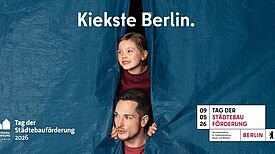 Ein Mann und ein Kind blicken aus einer blauen Plane unter dem Schriftzug „Kiekste Berlin“ hervor.
