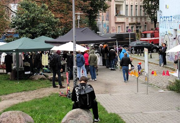 Menschen besuchen den Kleidertauschmarkt und Workshops beim Sasarcafé am Sasarsteig.