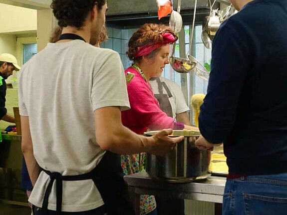 Drei Menschen stehen in einer Küche und kochen zusammen.