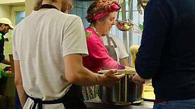 Drei Menschen stehen in einer Küche und kochen zusammen.