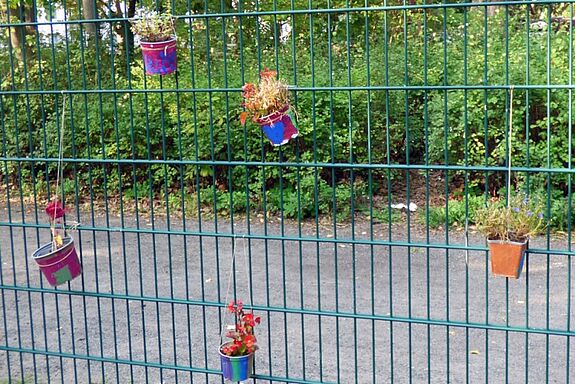 Die bunt bemalten Blumentöpfe zieren den Zaun der Verkehrsschule. (Bild: Julian Krischan)