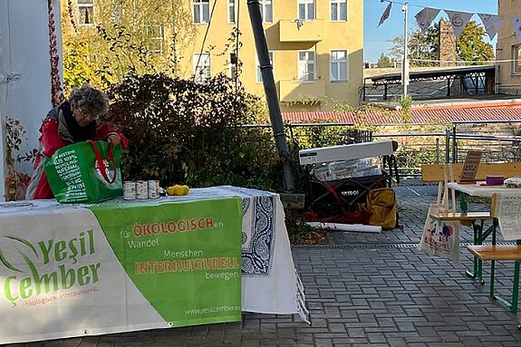 An einem Stand von „Yesil Çember“ mit Informationsmaterialien und Lebensmitteln packt eine Mitarbeitende Sachen aus.