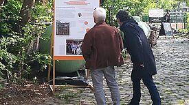 Angemeldete Besucher der Ausstellungseröffnung betrachten eine Schautafel. (Foto: Dominique Hensel)