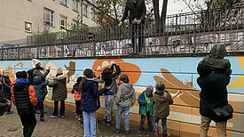 Schulleiter Axel Gotthardt weiht sichtlich erfreut die neue Wandbemalung ein. (Bild: QM Mehringplatz)