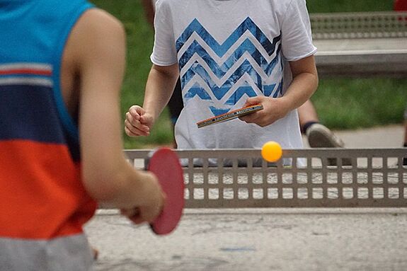 Zwei Kinder spielen Tischtennis an einer Platte im Quartier.