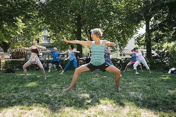 Menschen nehmen an einem Fitnesskurs im Freien im Rahmen des KiezFit-Projekts teil.