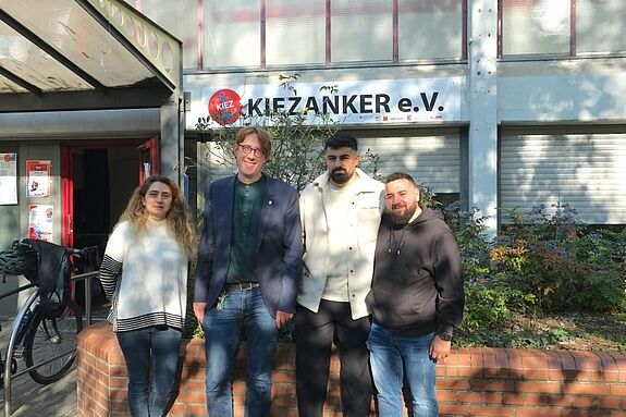 Neuköllns Stadtrat Jochen Biedermann steht gemeinsam mit drei Projektbeteiligten vor dem Gebäude des Kiezanker e.V.
