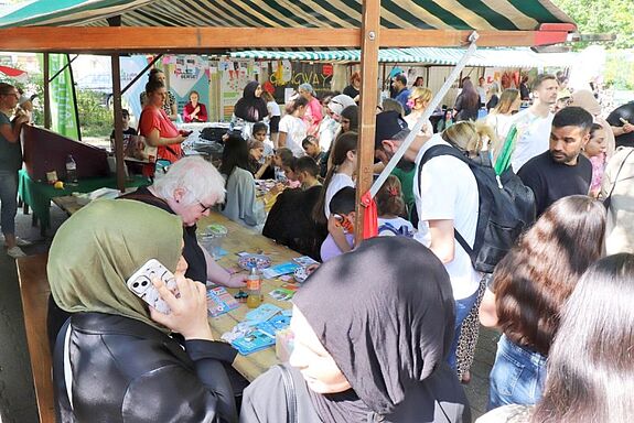 Viele Menschen jeden Alters versammeln sich an Ständen mit Bastel- und Informationsangeboten beim Sommerfest im QM-Gebiet Titiseestraße.