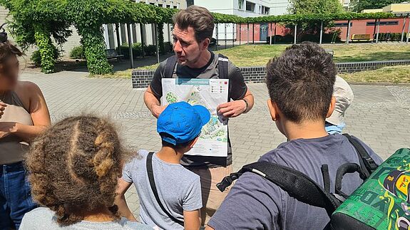 Mehrere Personen betrachten während einer Projektaktion gemeinsam einen Gartenplan für naturnahe Flächen im QM-Gebiet Thermometersiedlung.