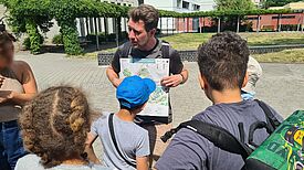 Mehrere Personen betrachten während einer Projektaktion gemeinsam einen Gartenplan für naturnahe Flächen im QM-Gebiet Thermometersiedlung.