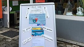 Das Willkommensschild am Eingang des TauschTreffs lädt zum Austausch im Nachbarschaftscafé ein und informiert über die Postkarten-Aktion. (Bild: Kerrin Thomsen (NUSZ))