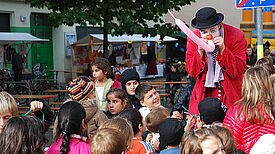 Ein Clown bläst Luftballons für Kinder auf.