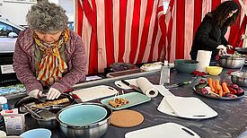 Zwei Projektmitglieder bereiten am Stand auf dem Kranoldplatz gefüllte Pfannkuchen für den Ernährungstag vor.