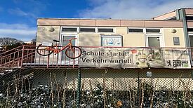 Ein orangefarbenes Fahrrad hängt am Geländer der Jugendverkehrsschule Gottschedstraße.