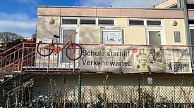 Ein orangefarbenes Fahrrad hängt am Geländer der Jugendverkehrsschule Gottschedstraße.