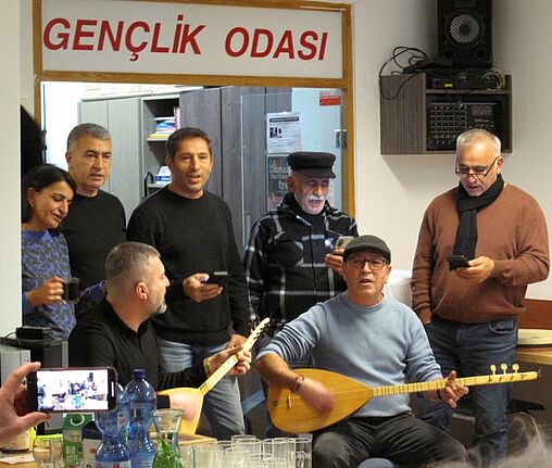 Eine Gruppe von Menschen singt und spielt traditionelle anatolische Musik mit der Laute Baglama.