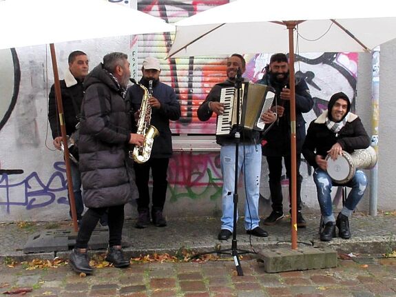 Eine Balkanband spielt unter Regenschirmen beim Sasarcafé auf dem Sasarsteig.