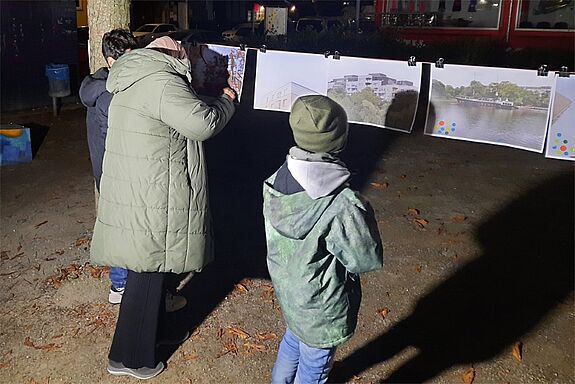 Drei Personen kleben Punkte auf ihre Lieblingsbilder. 