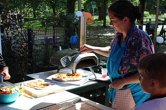 Die Anwesenden aßen selbstgemachte Pizza, Salate und Kuchen vom Buffet oder Softeis aus der Eismaschine, die das Stadtteilzentrum Steglitz mitgebracht hatte. (Bild: QM Thermometersiedlung)
