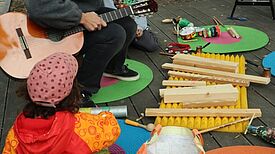 Kinder bauen mit Theaterpädagoginnen auf der Grüntaler Promenade Instrumente aus Müll.