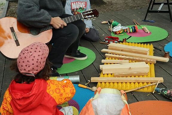 Kinder bauen mit Theaterpädagoginnen auf der Grüntaler Promenade Instrumente aus Müll.