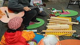 Kinder bauen mit Theaterpädagoginnen auf der Grüntaler Promenade Instrumente aus Müll.