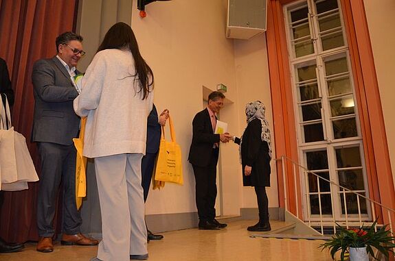 Eine Frau erhält bei der Dankesfeier des QMs Sonnenallee Süd / High-Deck-Siedlung eine gelbe Tasche als Anerkennung für ihr ehrenamtliches Engagement.