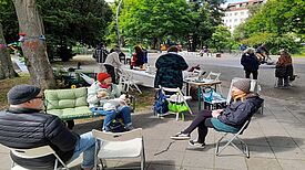 Personen sitzen im QM-Gebiet Harzer Straße auf einem Sofa und Stühlen und reden miteinander.