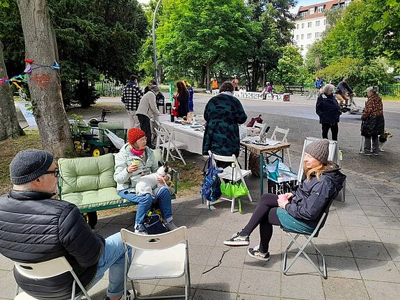 Personen sitzen im QM-Gebiet Harzer Straße auf einem Sofa und Stühlen und reden miteinander.