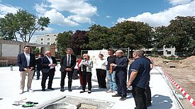 Bürgermeister Kai Wegner und Mitglieder von Senat und Bezirksamt stehen auf Gründungsplatte des Erweiterungsbaus der Jugendfreizeiteinrichtung SENFTE 10.  