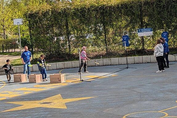 Mehrere Jugendliche spielen gemeinsam draußen Federball.